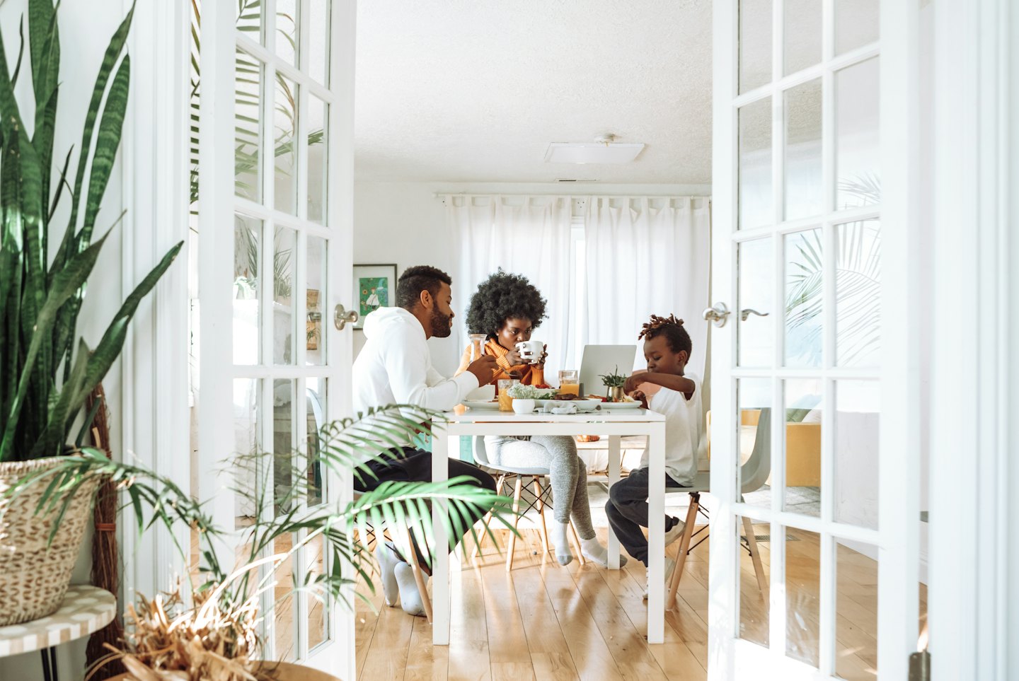 Family at a dining table with an open laptop.
